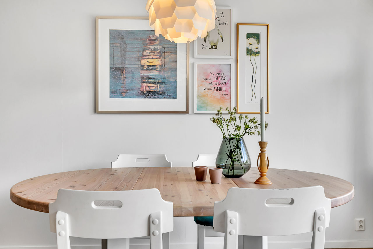 Spisebord med blomster under bildevegg i lys leilighet