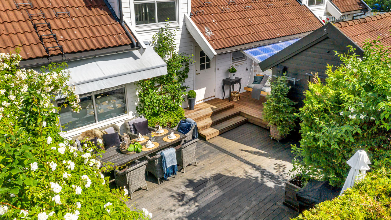 Solrik terrasse med utemøbler og planter sett fra dronen
