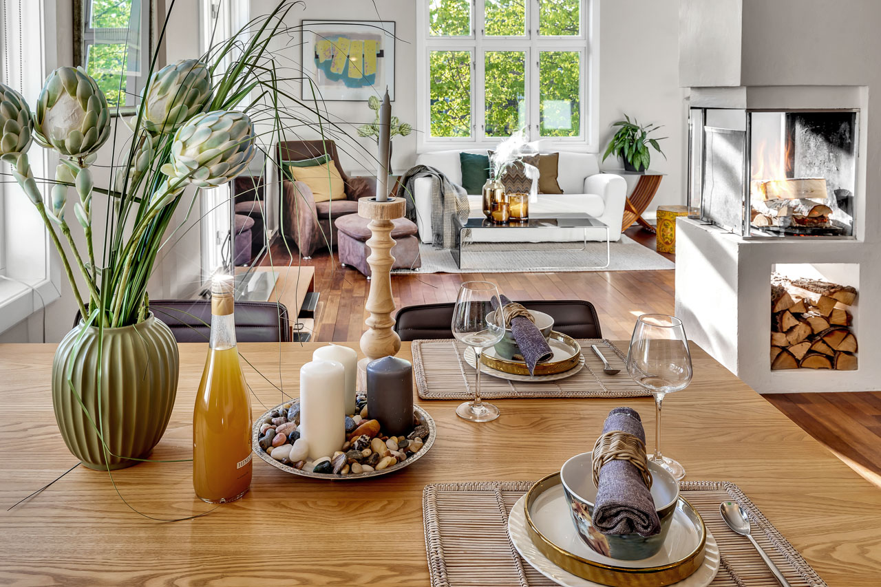 Spisebord med glass og drikke foran lys stue med planter og dagslys