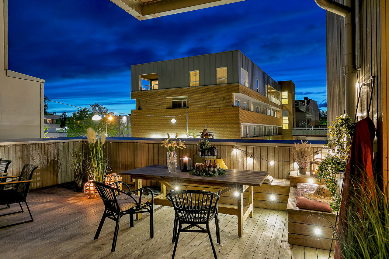 Takterrasse i skumringen med stoler og tent uteplass foran moderne bygg